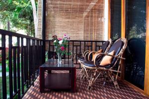 a balcony with two chairs and a table with a vase of flowers at Patnem Beach Cottages in Patnem