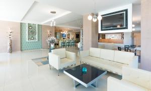 a living room with white furniture and a tv at Elinotel Sermilia Resort in Psakoudia