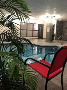 una silla roja sentada junto a una piscina en Grand Times Hotel – Aeroport de Quebec, en Quebec