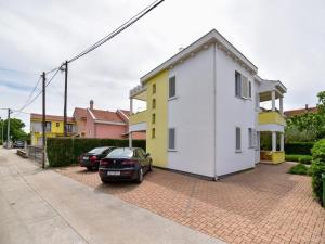 Biały i żółty dom z samochodami zaparkowanymi na podjeździe w obiekcie Apartment in Suko an near Sandy Beach w Sukošanie