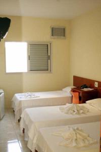 a room with three beds and a desk and a window at Hotel Morada do Sol in Araxá