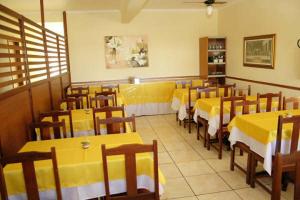 a restaurant with yellow tables and wooden chairs at Hotel Morada do Sol in Araxá
