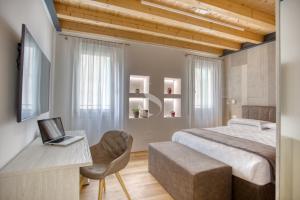 1 dormitorio con 1 cama y escritorio con ordenador portátil en Ca' dei Battuti Apartments, en Treviso