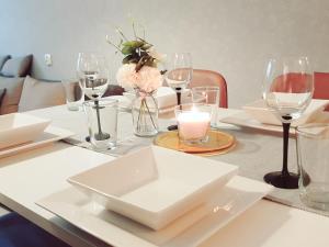 a table with white plates and wine glasses on it at Apartament Wągrowiec, Gabi - Remigiusz Kiszka in Wągrowiec