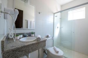 y baño blanco con lavabo y ducha. en Hotel Ryan, en Balneário Camboriú