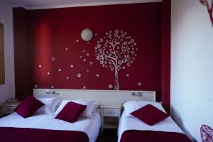 two beds in a room with a tree on the wall at Hotel Il Crinale in Grizzana