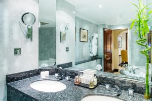 a bathroom with a sink and a large mirror at Millennium Gloucester Hotel London in London