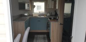 a small kitchen with blue cabinets and a sink at Bonnie Gorm in Boat of Garten