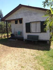 a small white house with a bench in the yard at cabañas sector peñuelas in Coquimbo