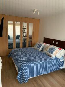 Schlafzimmer mit einem blauen und weißen Bett und Spiegeln in der Unterkunft Santiago Encomenderos el Golf in Santiago