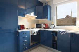 une cuisine bleue avec des placards bleus et une fenêtre dans l'établissement COLMAR - Appartement "LE ROESSELMANN 2" -, à Colmar
