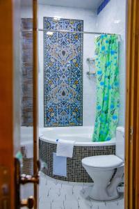 y baño con bañera, aseo y ducha. en Old Gate Hotel, en Bukhara