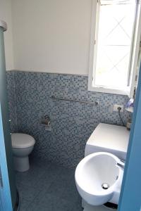 a bathroom with a toilet and a sink and a window at Villa Imma in Torre Lapillo +23 photos
