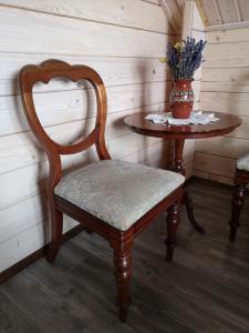 uma cadeira de madeira e uma mesa com um vaso de flores em Mazurski Staw em Goldap