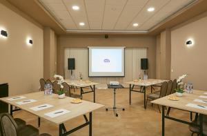 a conference room with tables and a white screen at Árnyas Panzió Gödöllő in Gödöllő