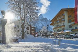 una calle cubierta de nieve con edificios y una montaña en Hotel Stern en Ehrwald