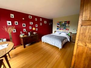 a bedroom with red walls and a bed and a wooden floor at Homestay Le Corbusier 5 ieme Rue in Firminy