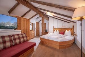 a bedroom with a large bed and a red couch at Wellnessresort Seiwald **** Superior in Going am Wilden Kaiser