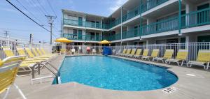 a swimming pool in front of a hotel with yellow chairs at Shangri-La Motel in Ocean City