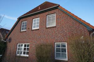 una casa de ladrillo rojo con ventanas blancas. en Günnis Perle am Harleufer, en Carolinensiel