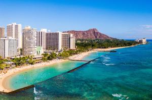 eine Luftansicht auf einen Strand mit Gebäuden und das Meer in der Unterkunft Waikiki Monarch Hotel in Honolulu
