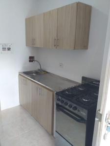 a kitchen with a stove and wooden cabinets at Apartamento con piscina in Montería