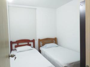 two beds in a room with white sheets at Apartamento con piscina in Montería