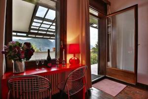 um quarto com um balcão vermelho com cadeiras e uma janela em Villa la Grona em Menaggio