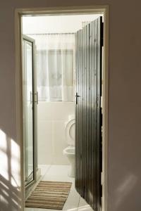 a bathroom with a toilet and a glass door at KhayaLethu Vic Falls in Victoria Falls