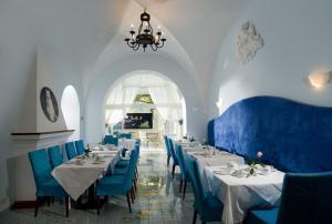 a dining room with white tables and blue chairs at Albergo Gatto Bianco in Capri