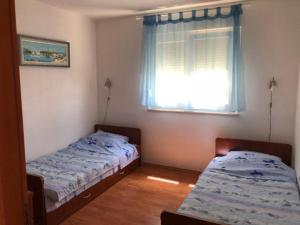 dwa łóżka w pokoju z oknem w obiekcie Lili Murter w mieście Murter