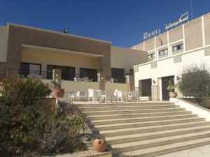 ein Gebäude mit Stühlen und Treppen davor in der Unterkunft Sufetula Hotel in Sbeitla