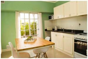 a kitchen with green walls and a table and a window at El Piso de Arriba in Las Flores