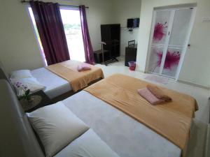 a room with two beds and a window at Huda Inn in Pantai Cenang
