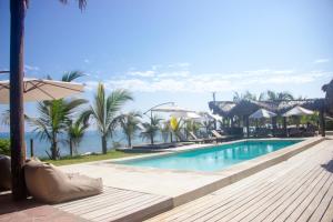 a pool at a resort with palm trees and umbrellas at Hoja de Palma Bungalows in Canoas de Punta Sal