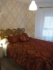 1 dormitorio con 1 cama con edredón rojo y ventana en Bnap Gesta, en Oviedo