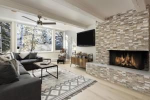 sala de estar con chimenea de ladrillo y TV en Chateau Snow Unit 202, Renovated Condo with Great Natural Light, Excellent Location, en Aspen