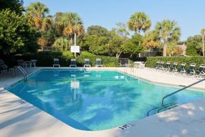 une grande piscine avec des chaises et des palmiers dans l'établissement Fairway Dunes 3, à Isle of Palms