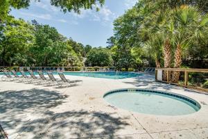 a swimming pool with lounge chairs and trees at Inlet Cove 11 in Kiawah Island