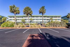 a parking lot in front of a hotel with palm trees at Sea Cabin 228-B in Isle of Palms