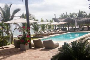 a swimming pool with lounge chairs and umbrellas at Hoja de Palma Bungalows in Canoas De Punta Sal