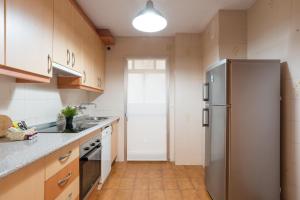 eine Küche mit einem Kühlschrank aus Edelstahl und Holzschränken in der Unterkunft Virginia Beach & private terrace by ELE Apartments in Málaga