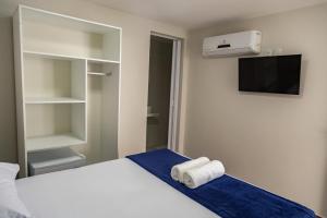 um quarto com uma cama branca e uma televisão e uma cama gmaxwell gmaxwell em Pousada Maresia Unique Beira Mar em Porto de Galinhas