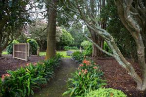 een pad door een tuin met bomen en bloemen bij Tairoa Lodge in Hawera