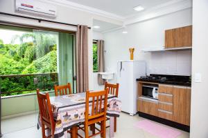 a kitchen with a table and chairs and a window at Canto dos Pássaros Flat - Canasvieiras in Florianópolis