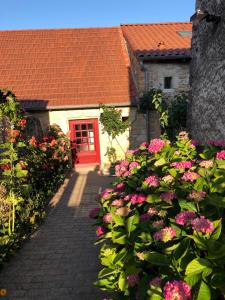 uma casa com uma porta vermelha e algumas flores em Gîte de la moinette em Azé