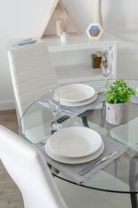 a glass table with plates and wine glasses on it at Brisbane City Apartments (Tank St CBD) in Brisbane