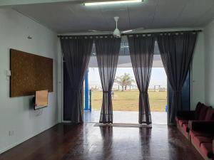 a living room with a large window with curtains at ALA Beach Lodge - Ketapang Homestay in Kota Bharu