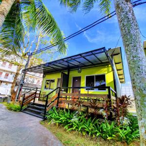 a yellow house with a porch and a palm tree at Casa Fina Fine Homes in Pantai Cenang