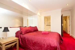 a bedroom with a red bed and a table at Sapphire in London